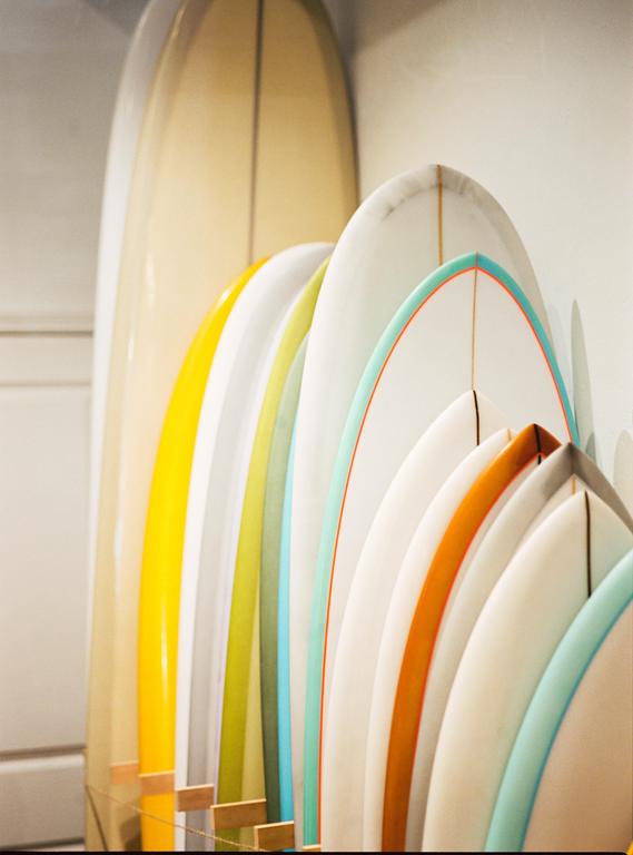 A collection of surfboards in various colors are arranged neatly in a row.