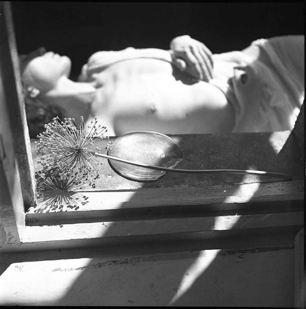A person is lying down with a flower and a spoon on a ledge in the foreground.