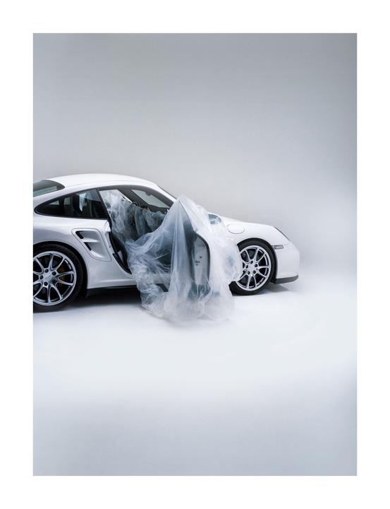 A white car with an open door has a plastic sheet draped over its interior.