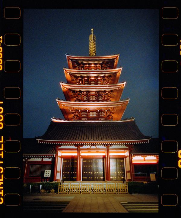 A multi-tiered pagoda with illuminated eaves stands against a dark blue night sky.