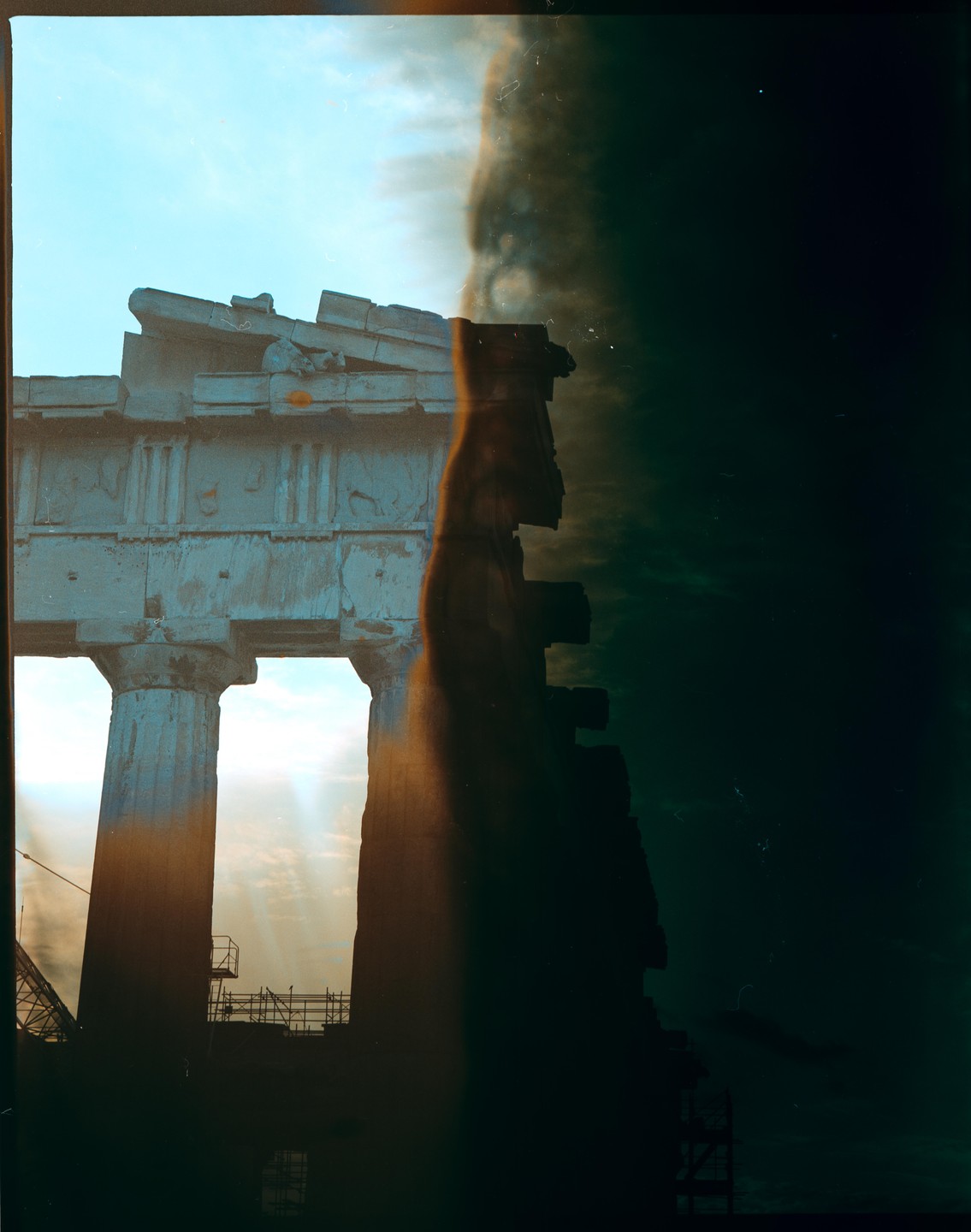 Sunlight shines through the columns of an ancient temple, with a dark, textured area on the right side of the image.
