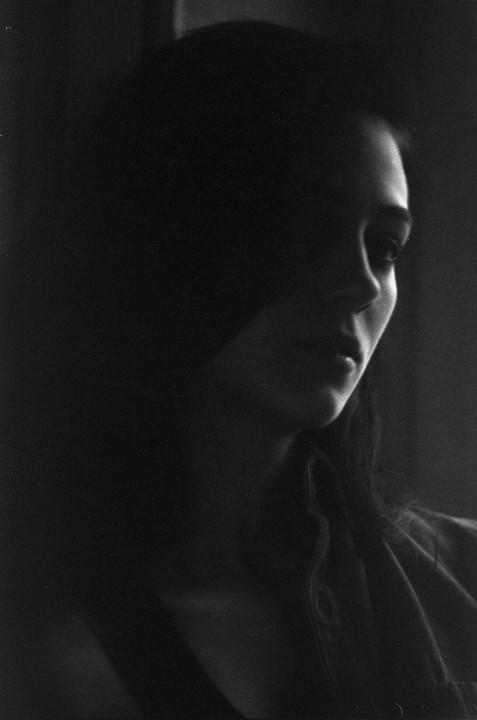A woman's face is partially obscured by shadow in a black and white portrait.