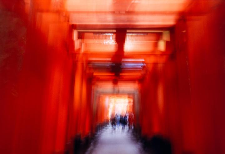 A blurry, motion-filled image shows a tunnel of red torii gates with people walking in the distance.