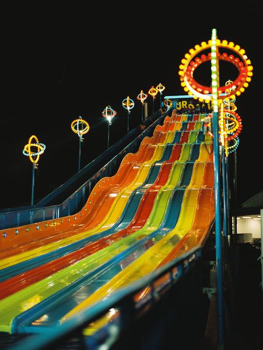 A colorful water slide with illuminated decorations is captured at night.