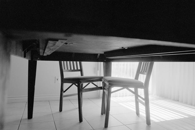 Two chairs are visible under a table, with light streaming in from a window.