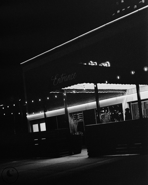 A building with an "Entrance" sign and string lights is seen at night.