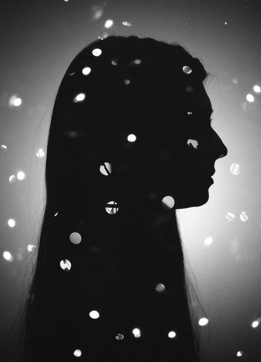 A woman's silhouette is visible in a double exposure with bokeh lights.