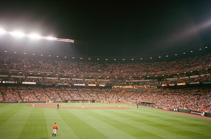A baseball game is being played at night in a stadium filled with spectators.