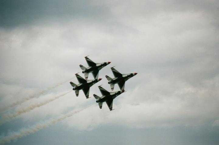 Four fighter jets fly in formation against a cloudy sky, leaving smoke trails behind them.