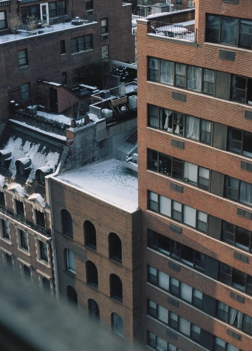 A high-angle view shows several brick buildings with snow-covered rooftops and windows.