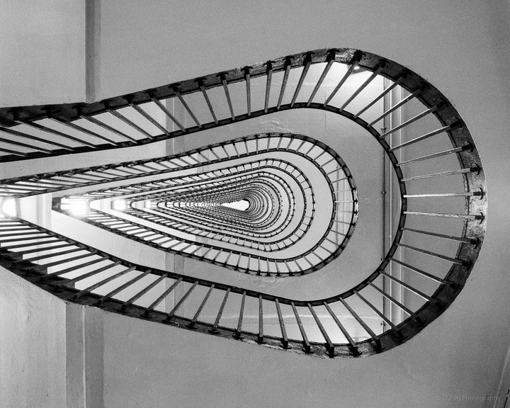 A view from below shows a spiral staircase with railings curving upwards.