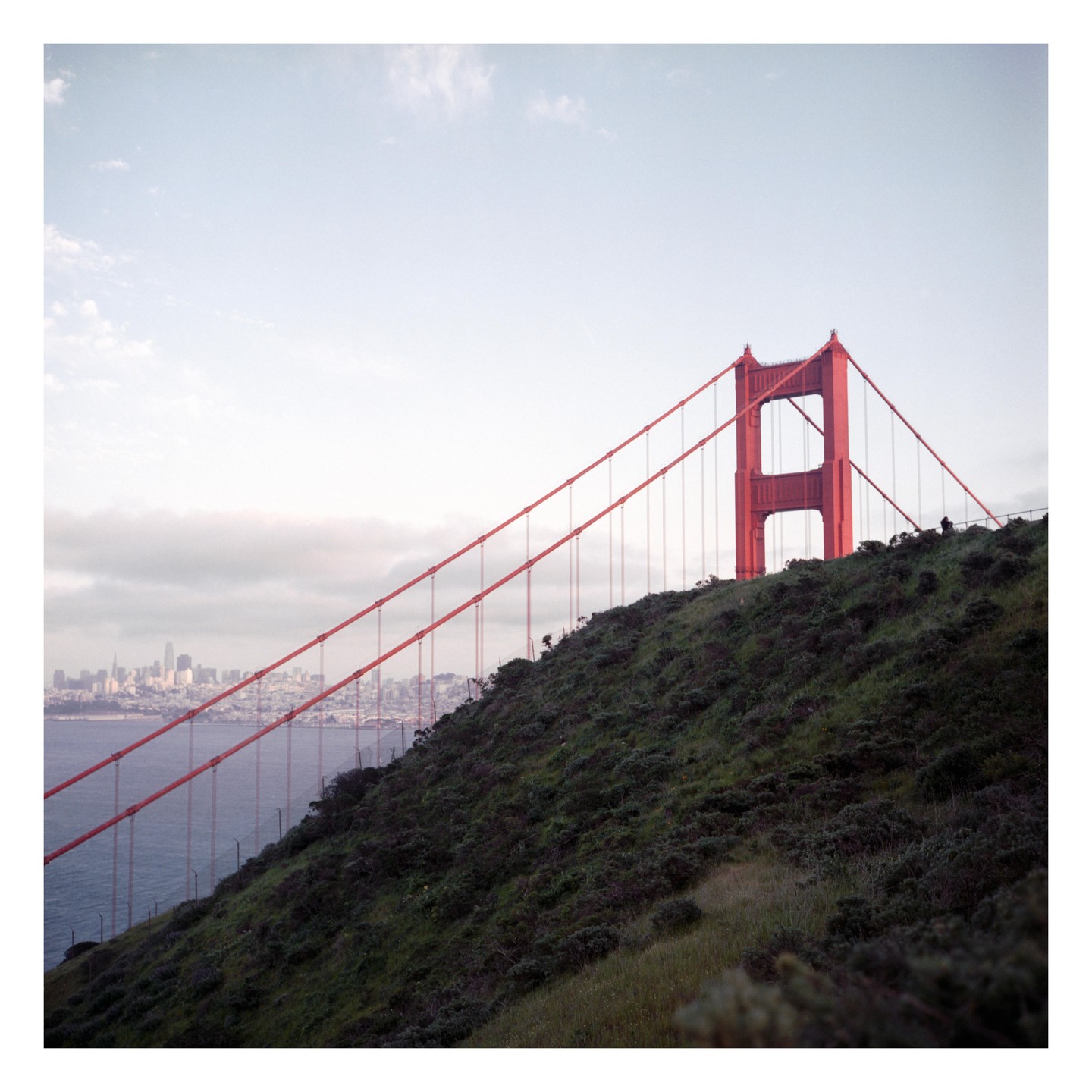 The Golden Gate Bridge is visible over a hill with the San Francisco skyline in the distance.