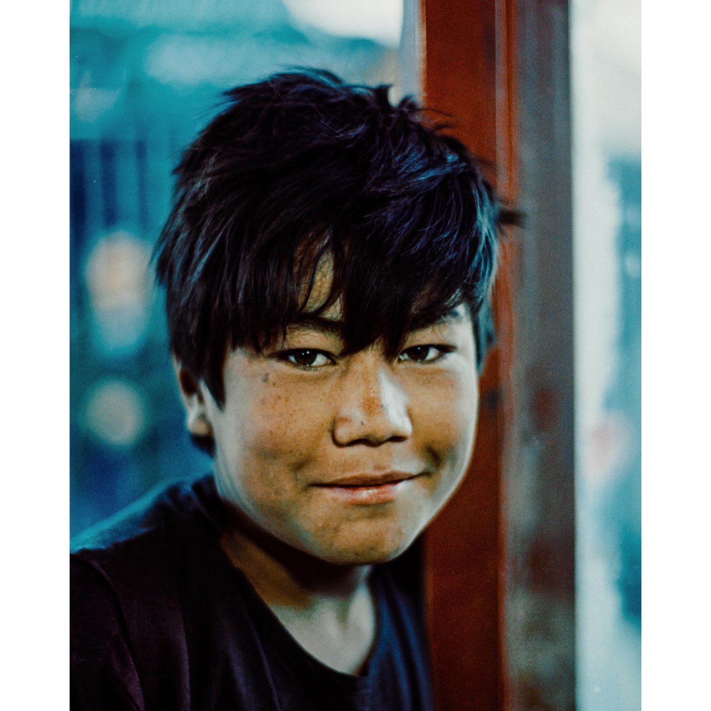 A boy with dark hair and freckles smiles at the camera.