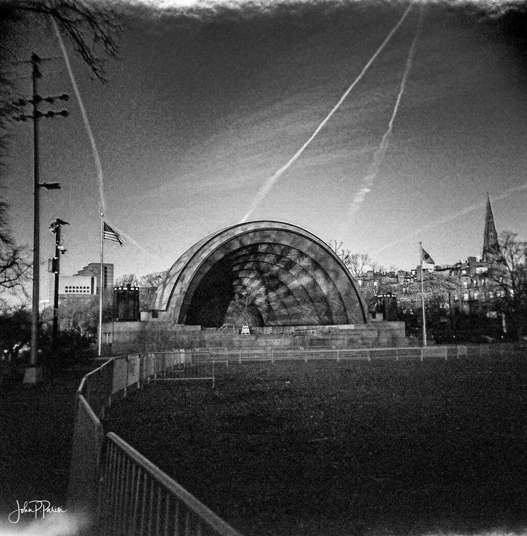 A black and white landscape shows a sound stage with a large arched roof and a tall steeple in the background.