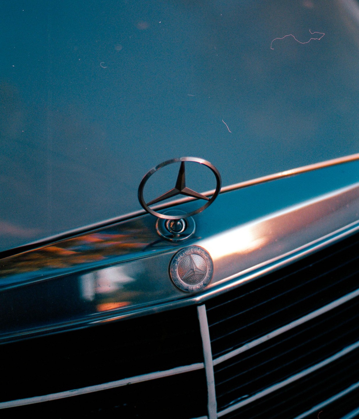 The Mercedes-Benz emblem is visible on the hood of a car.