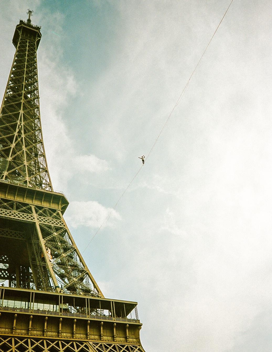 A man walks a tightrope next to the Eiffel Tower.