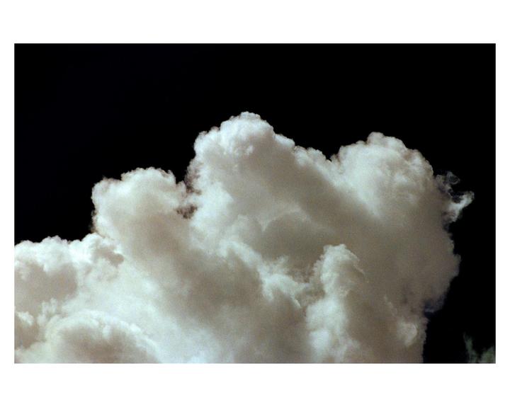 A large, bright cloud formation is set against a dark, almost black sky.