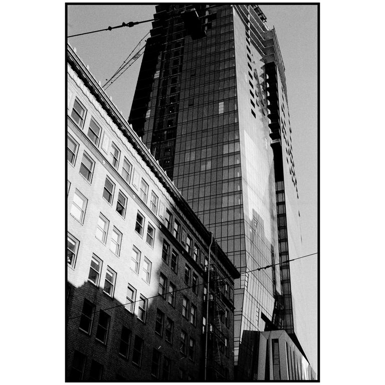 A tall glass skyscraper stands next to an older brick building with many windows.