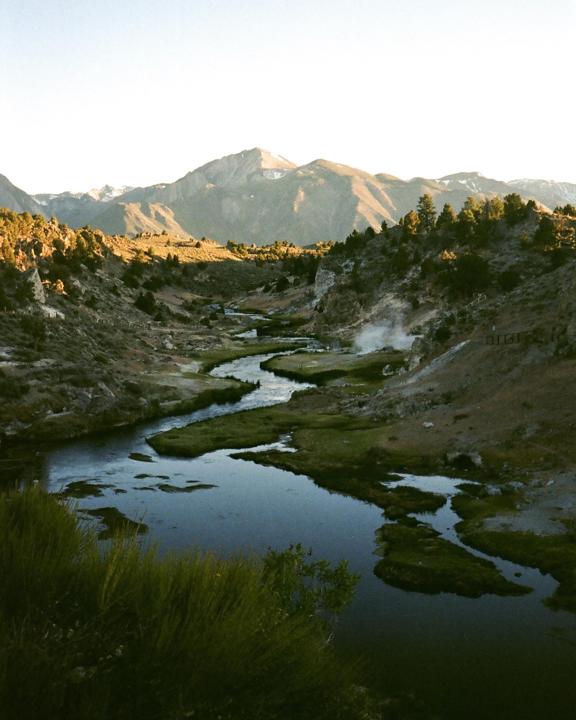 A winding river flows through a valley with mountains in the background.