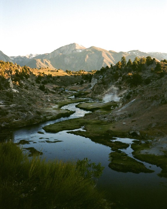 A winding river flows through a valley with mountains in the background.