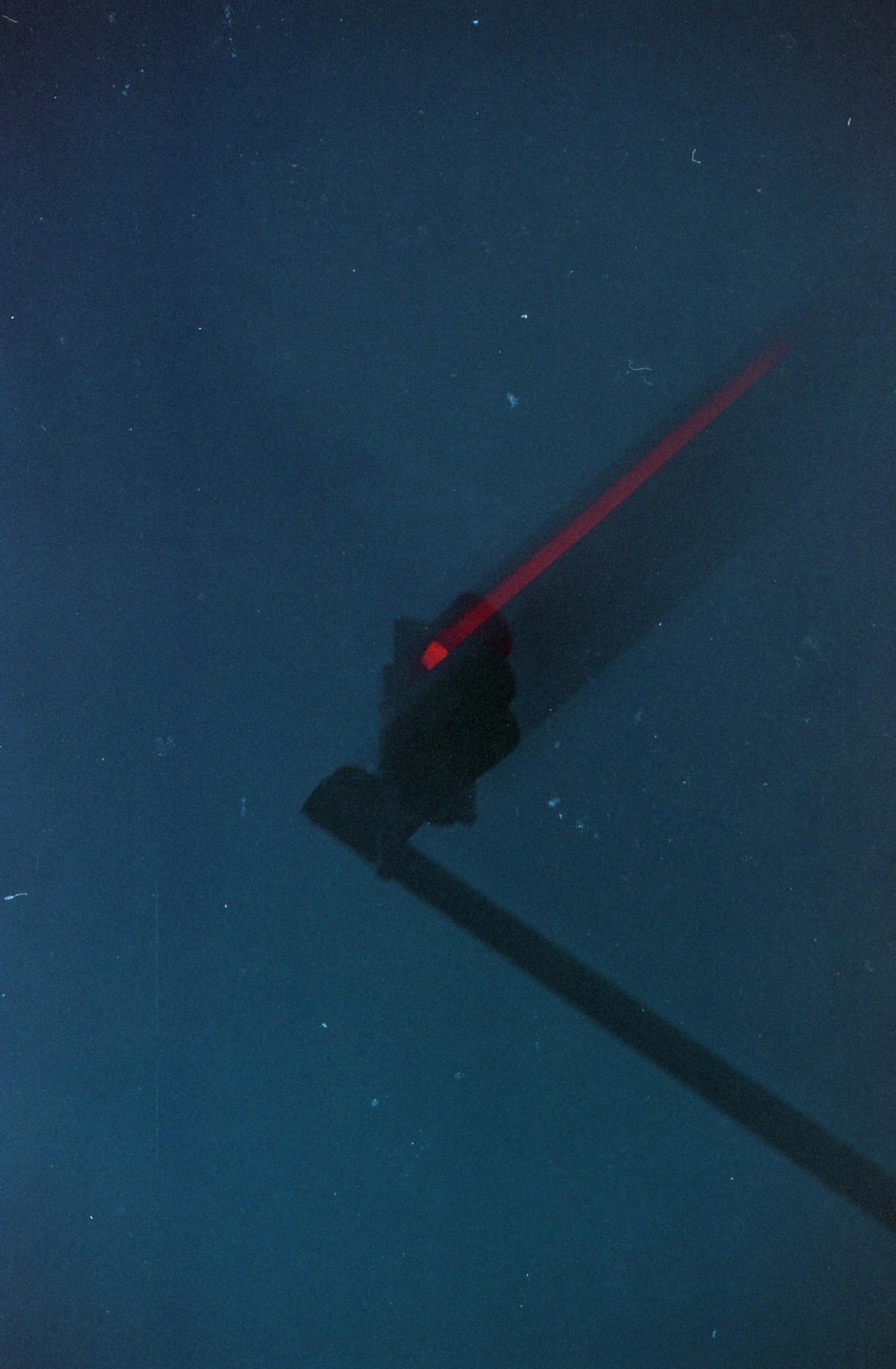 A red traffic light is visible in the dark with a long shadow extending from it.