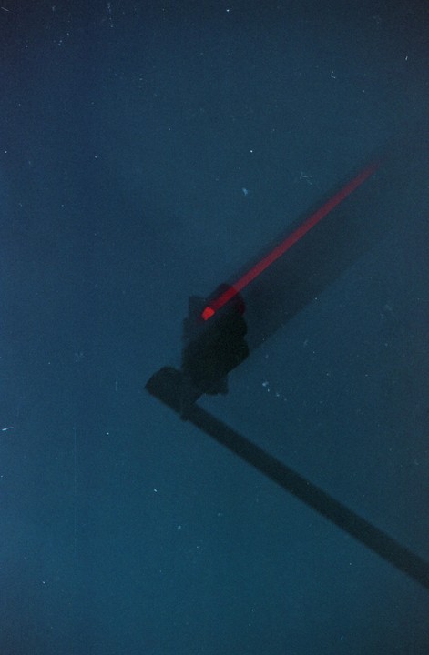 A red traffic light is visible in the dark with a long shadow extending from it.