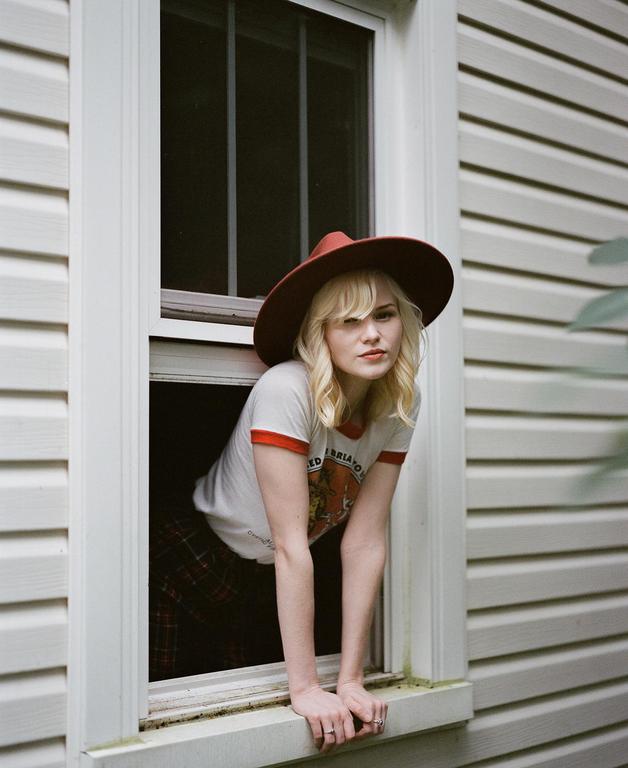 A woman wearing a hat leans out of a window.
