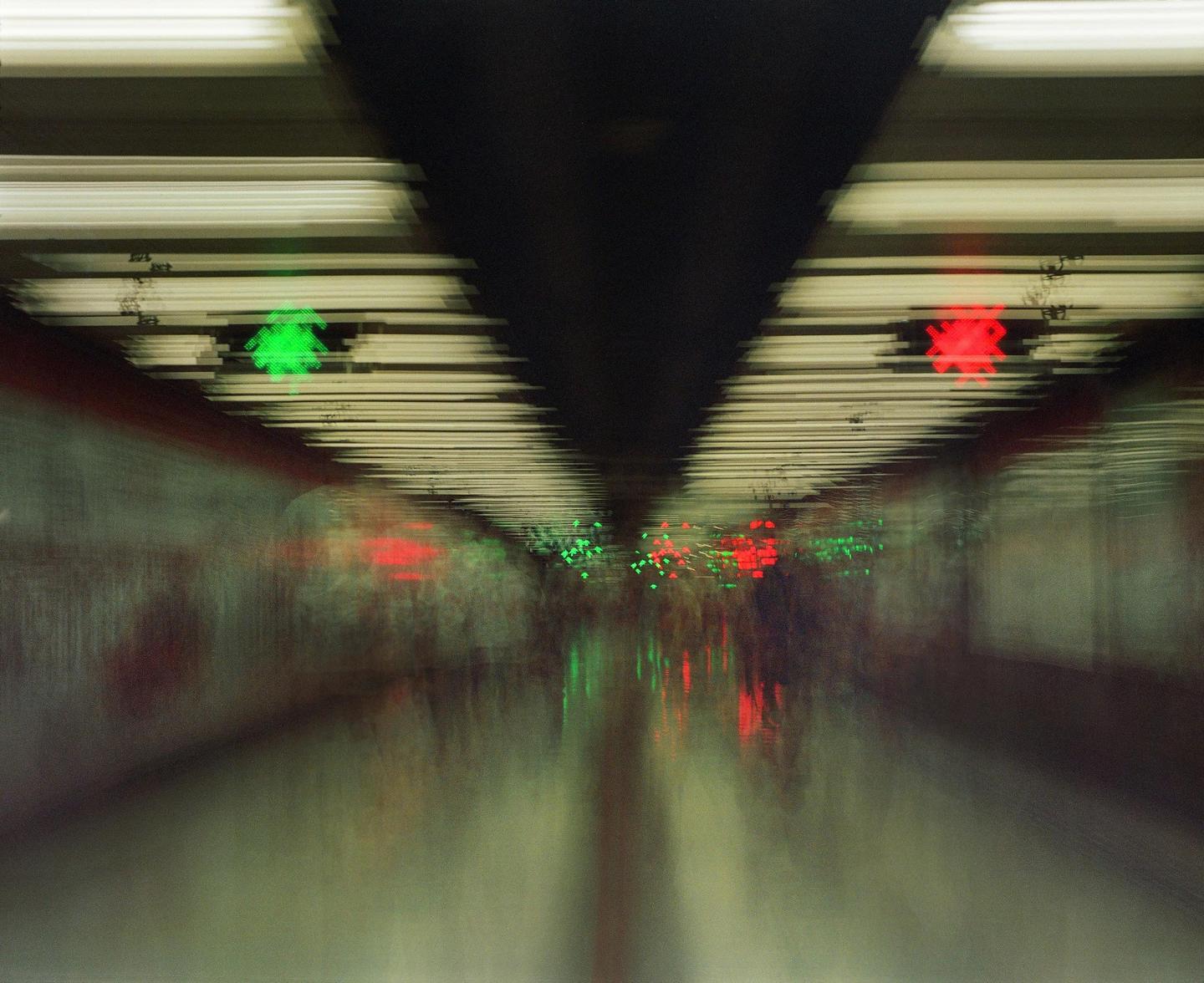 A blurry image shows a subway tunnel with green and red lights.