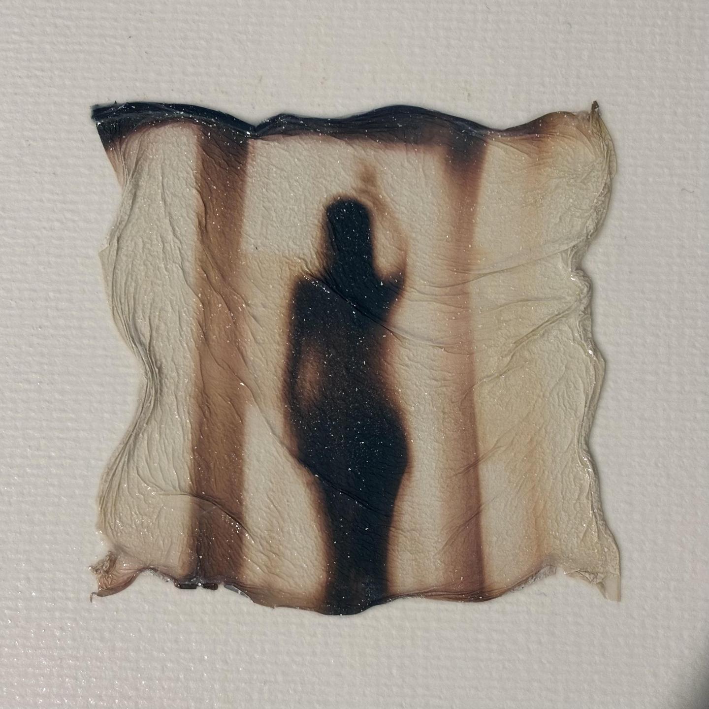 A dark silhouette of a woman is visible on a textured, wavy surface with vertical brown stripes.