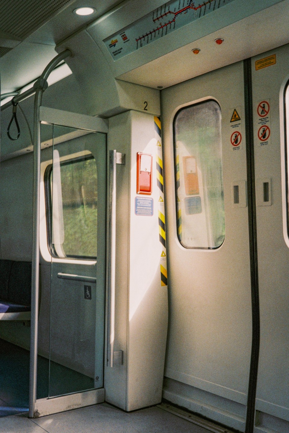 Sunlight streams into an empty subway car, illuminating the doors and floor.