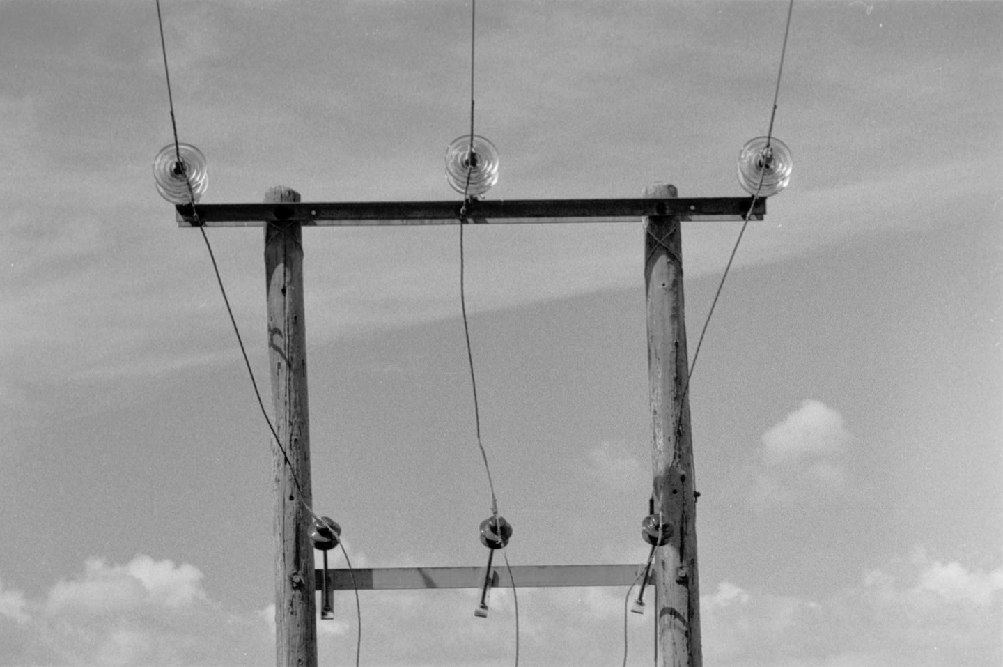 Three power poles with wires and insulators are visible against a cloudy sky.