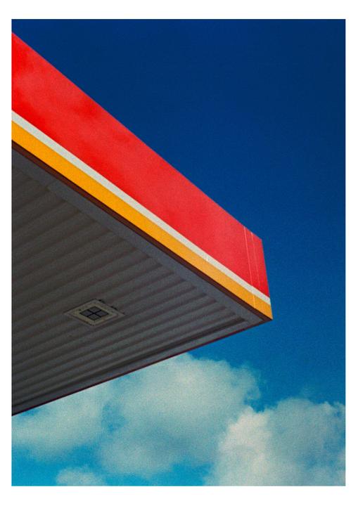 A red and yellow awning extends into a bright blue sky with white clouds.