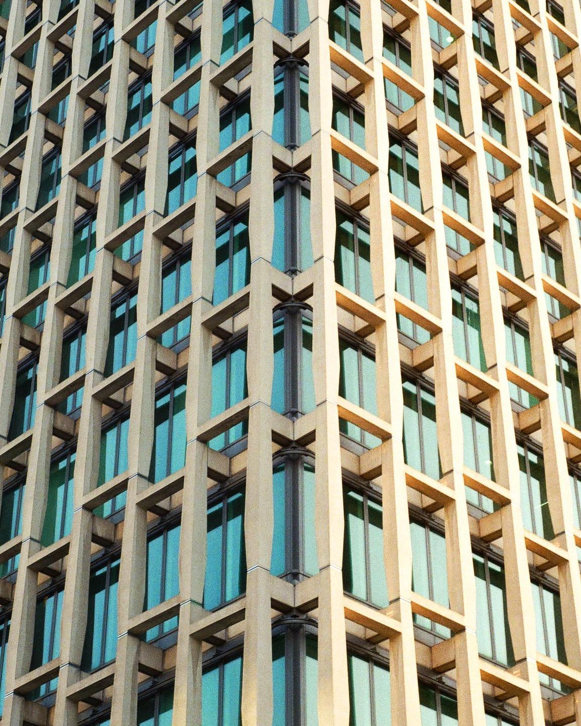 A modern building with a grid-like facade and blue-tinted windows is shown from a low angle.