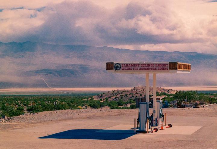A gas station with a sign for Panamint Springs Resort stands in a desert landscape with mountains in the background.