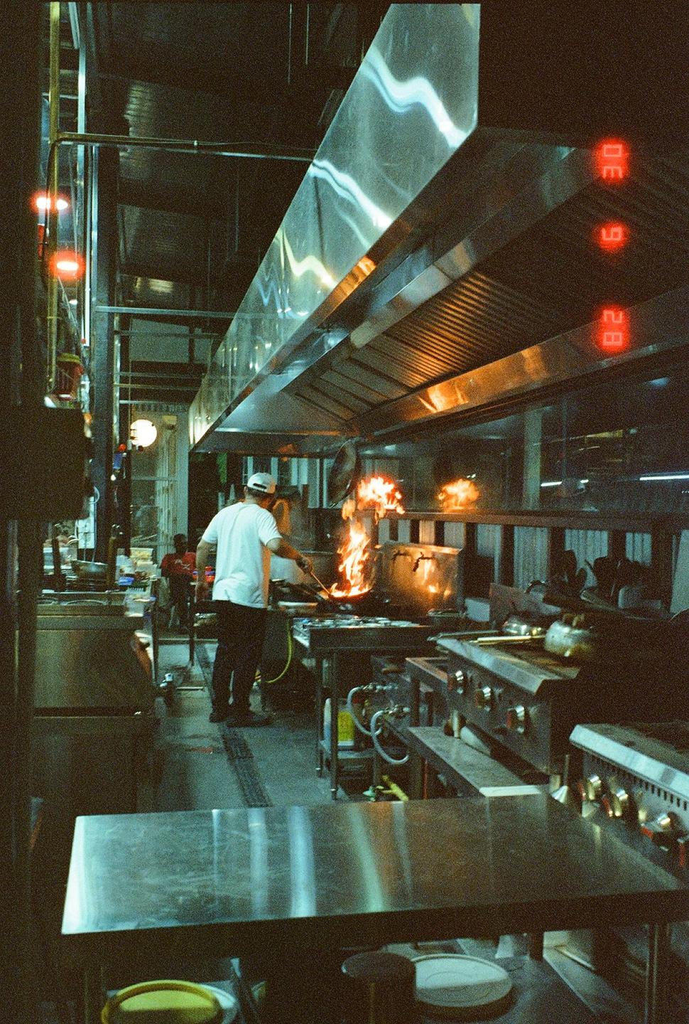 A chef cooks with a large flame in a commercial kitchen.
