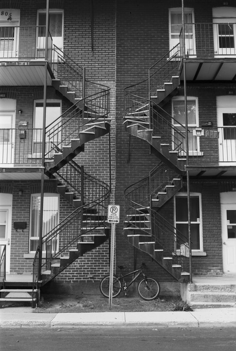 A bicycle is parked next to a brick building with two external spiral staircases.