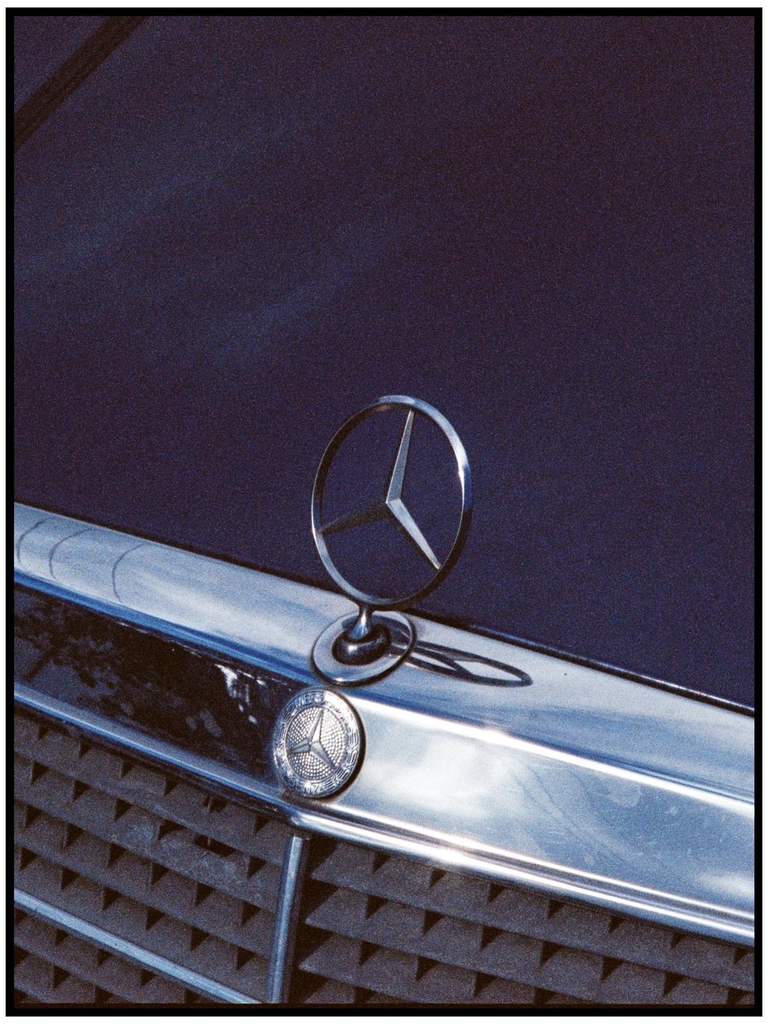 A close-up shows the Mercedes-Benz hood ornament and emblem on the front of a dark vehicle.