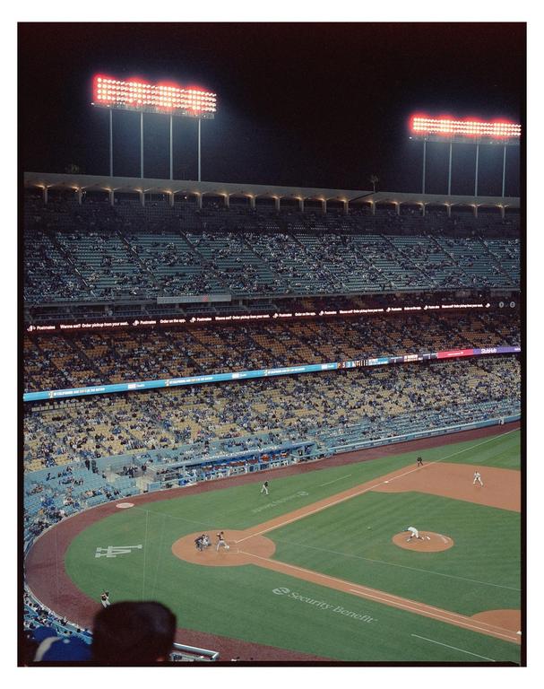 A baseball game is played at night in a stadium with many spectators.