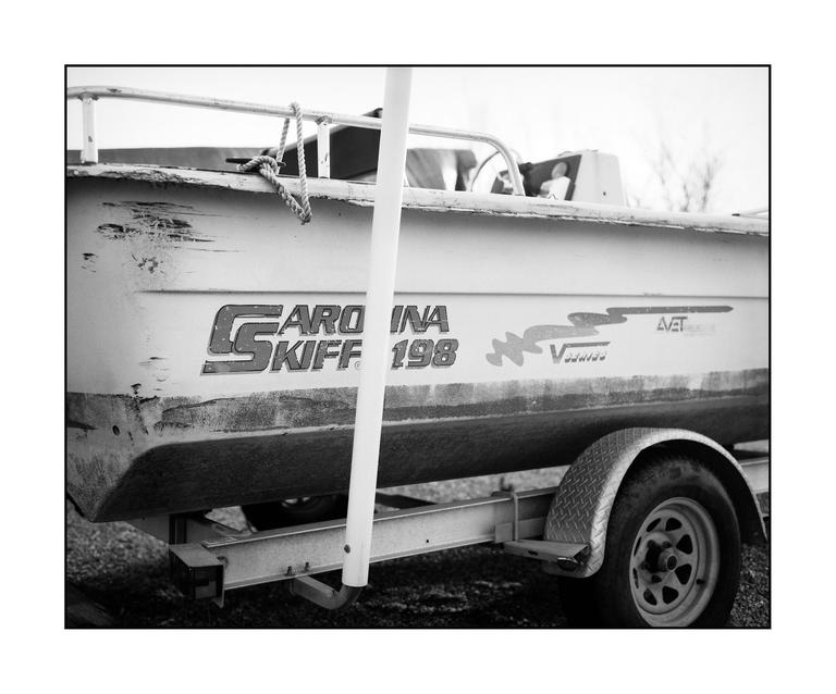 A boat on a trailer is parked outdoors.