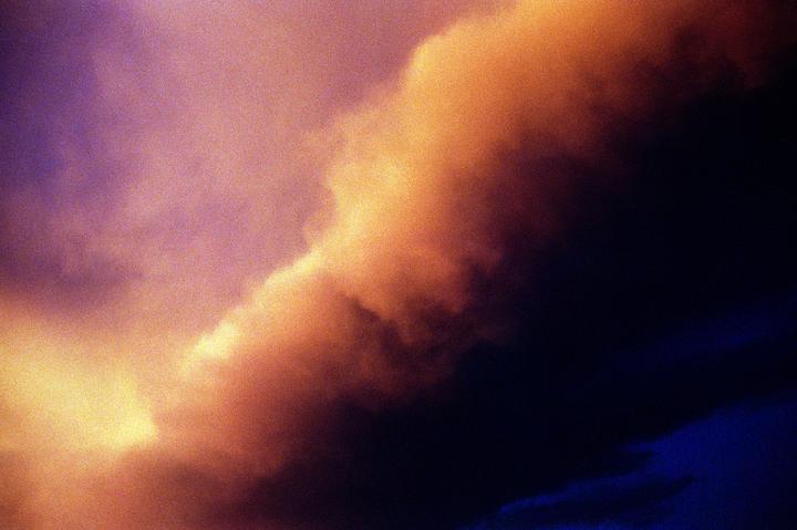 A dramatic sky is filled with clouds in shades of orange, purple, and dark blue.