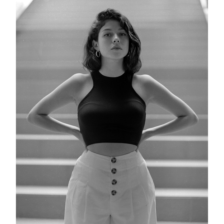 A woman stands with her hands on her hips in front of a staircase.