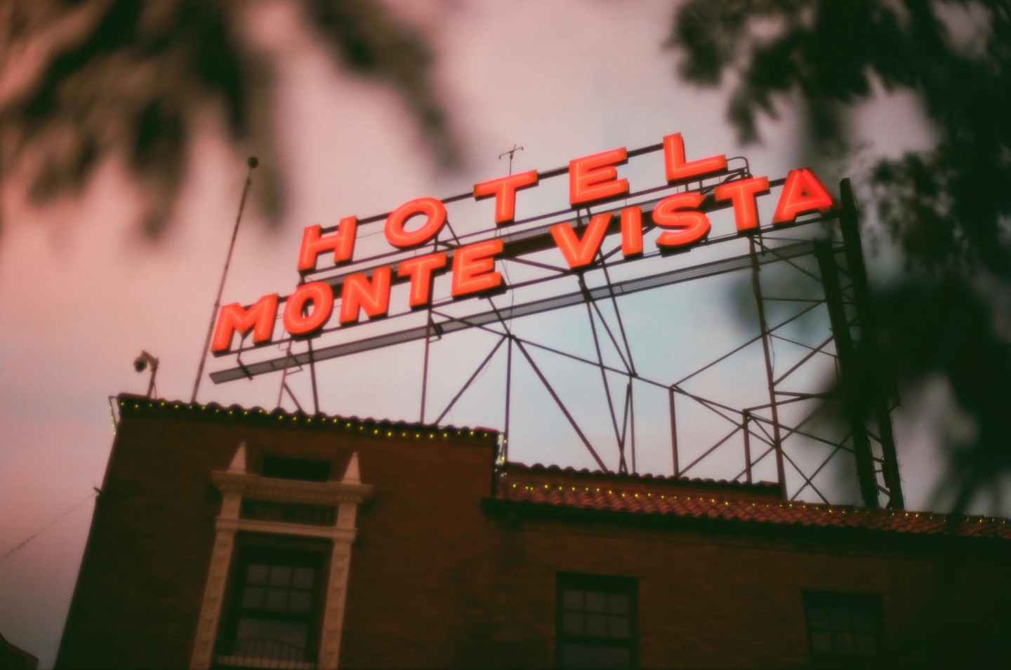 The Hotel Monte Vista sign with red neon letters is visible above a brick building with a tiled roof.