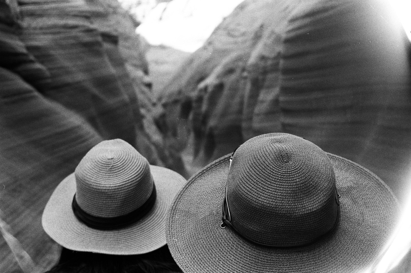 Two people wearing hats look down into Antelope Canyon.