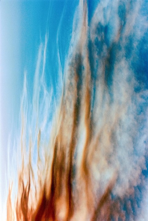 Wispy clouds streak across a blue sky, with some clouds appearing orange and brown.