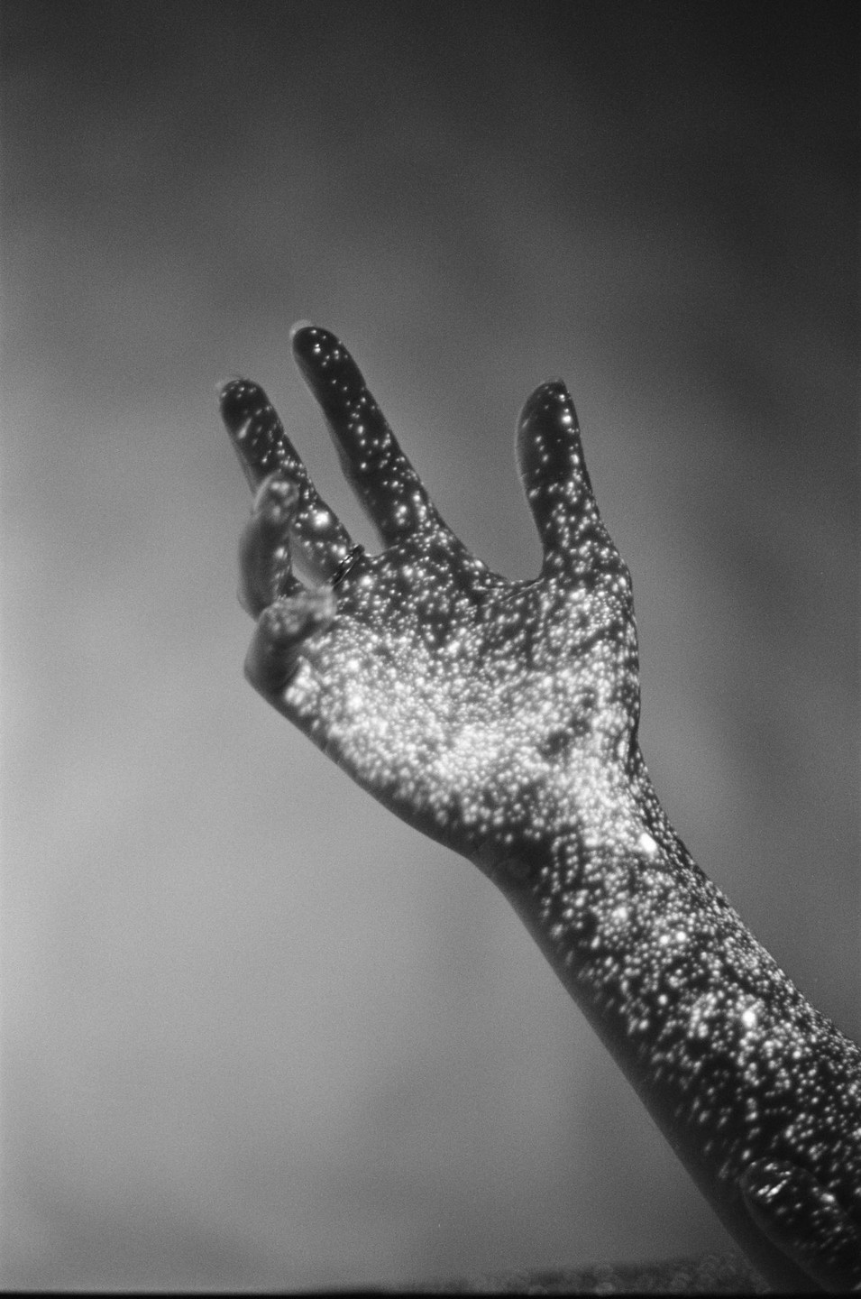 A hand is covered in many small, bright, circular lights against a plain background.