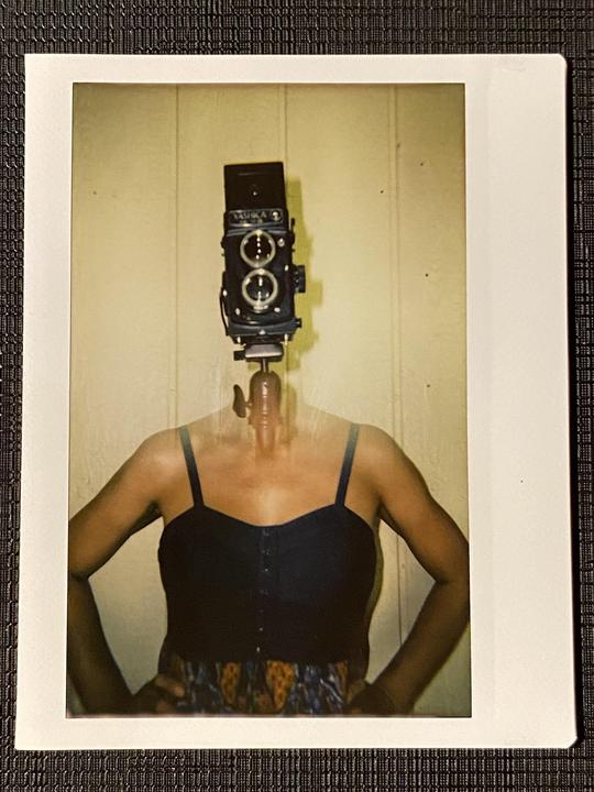 A camera is superimposed on a woman's body in a double exposure self-portrait.