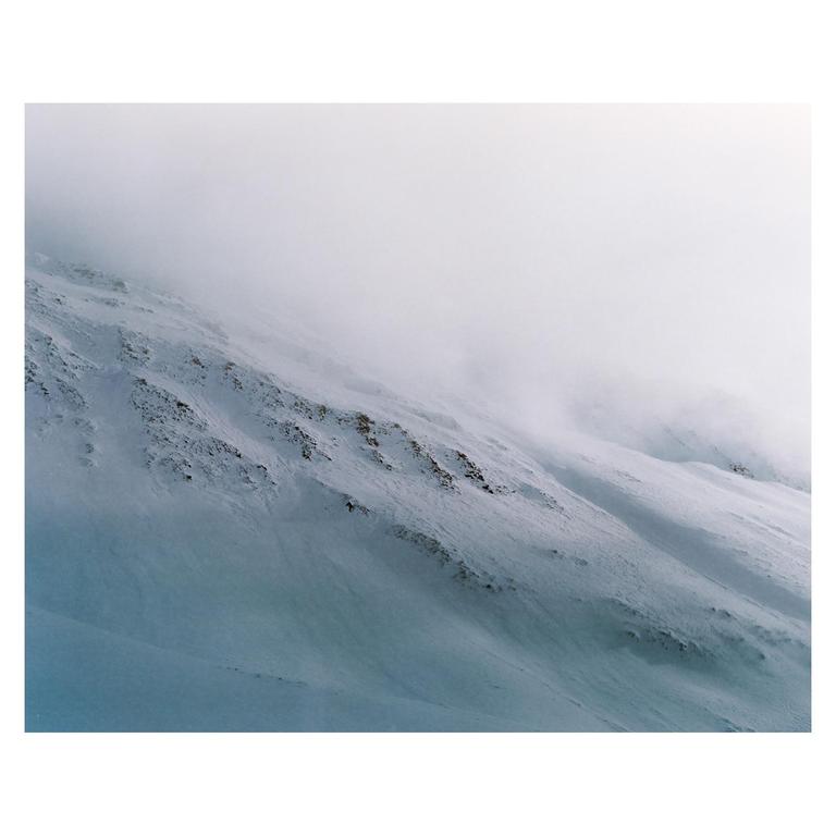 A snow-covered mountain slope is partially obscured by fog.