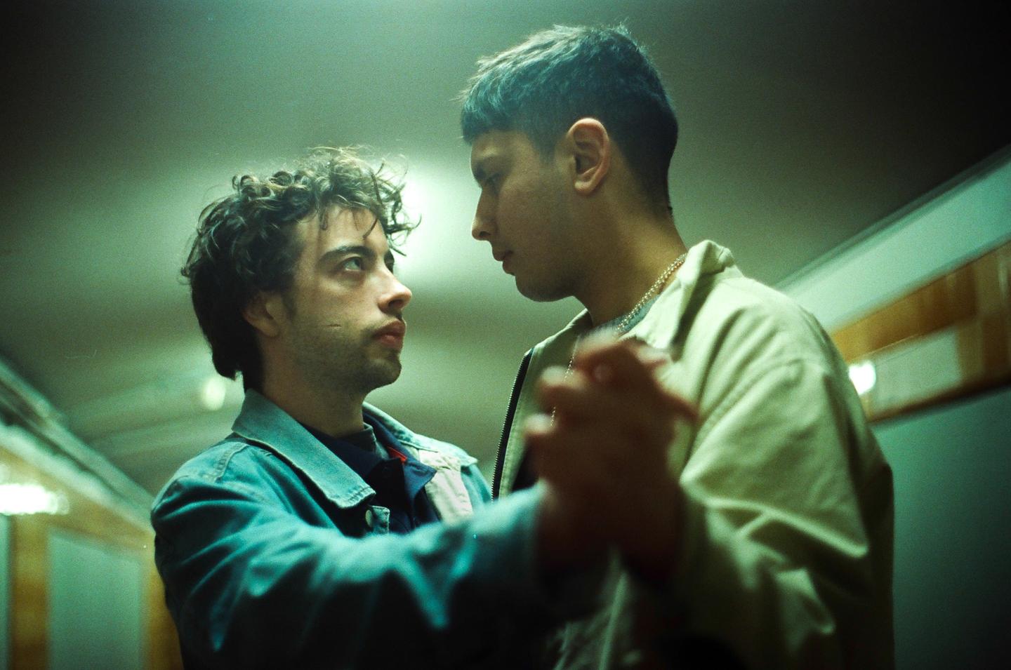 Two men are dancing together in a dimly lit room.