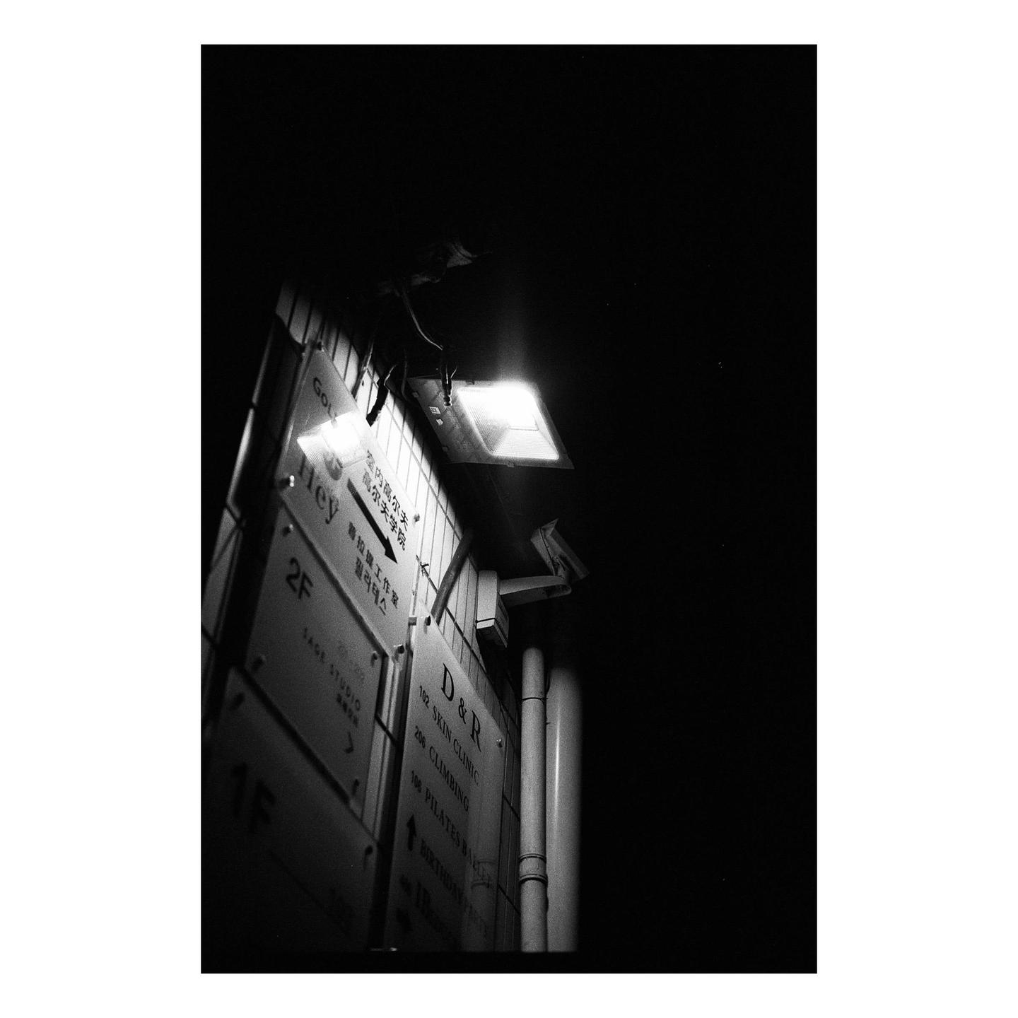 A building directory sign is illuminated by a bright light at night.