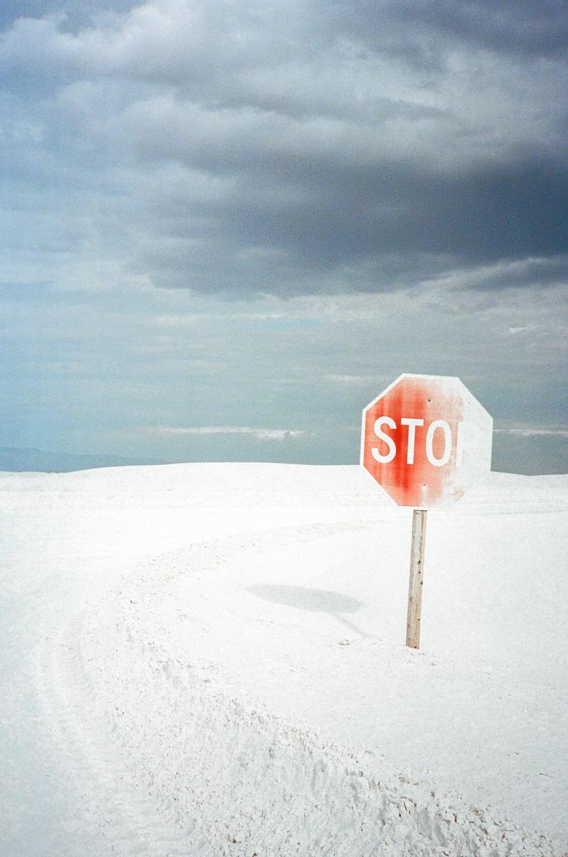 A stop sign stands in a white desert landscape under a cloudy sky.